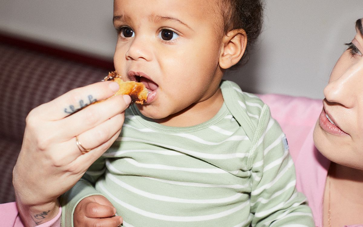 An infant sitting at a table, drinking from a cup