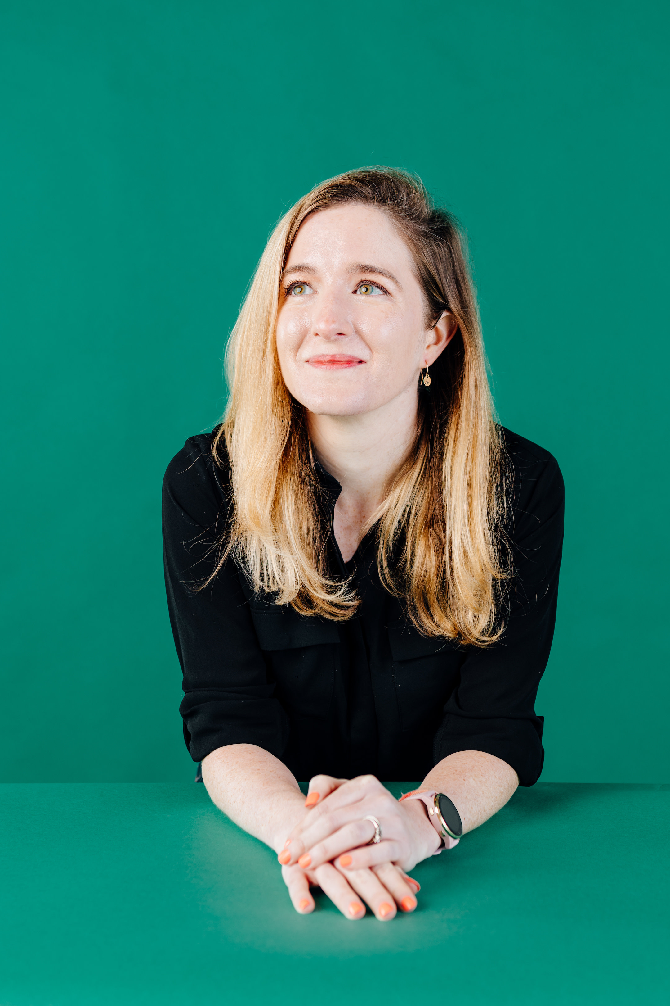 Author Keeley smiling and gazing up against a kelly green backdrop