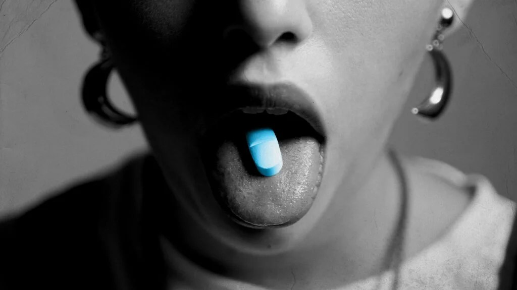 A person with a pill on their tongue.