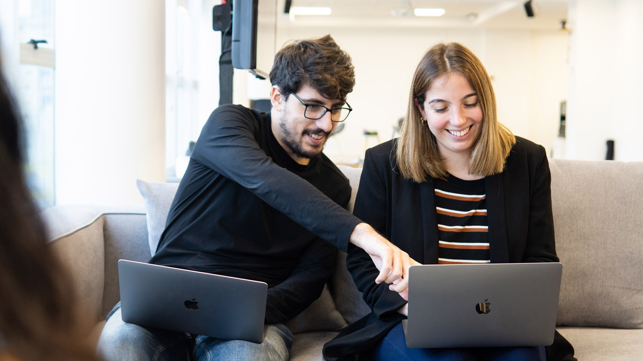 Two employees having a light chat on a couch in the office