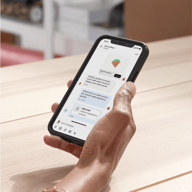 La proprietaria di un’azienda è seduta alla scrivania nel back office e usa Shopify Inbox per comunicare via chat con un cliente dal suo dispositivo mobile. Nella chat condivide un codice sconto per chiudere la vendita.