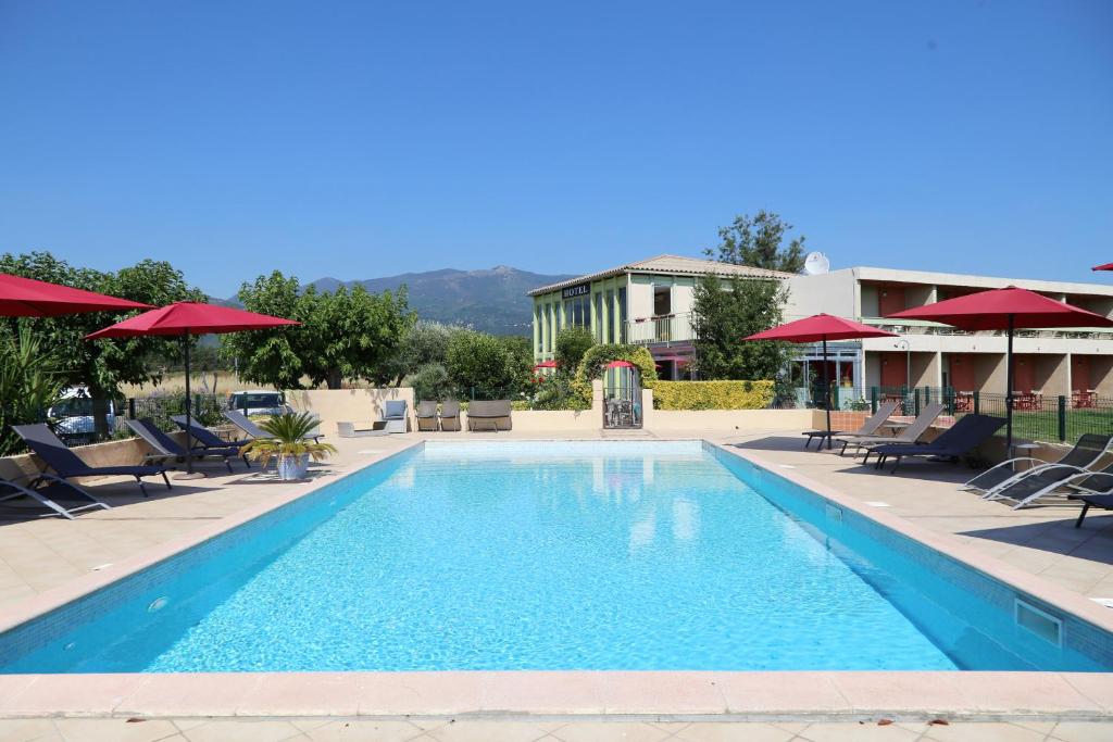 una piscina con sillas y sombrillas en un hotel en Hôtel Les Jardins en Lucciana