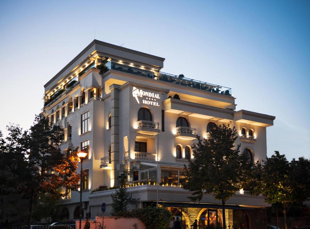 ein großes weißes Gebäude mit Beleuchtung in der Unterkunft Mondial Hotel in Tirana