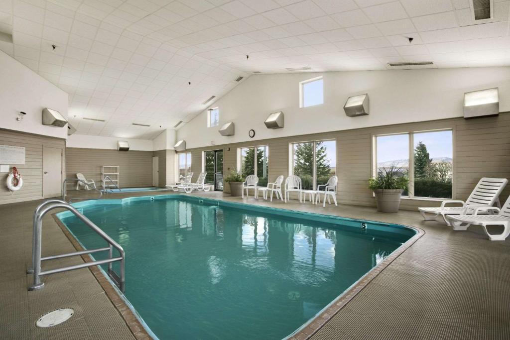 - une grande piscine dans un bâtiment avec des chaises dans l'établissement Days Inn by Wyndham Rapid City, à Rapid City