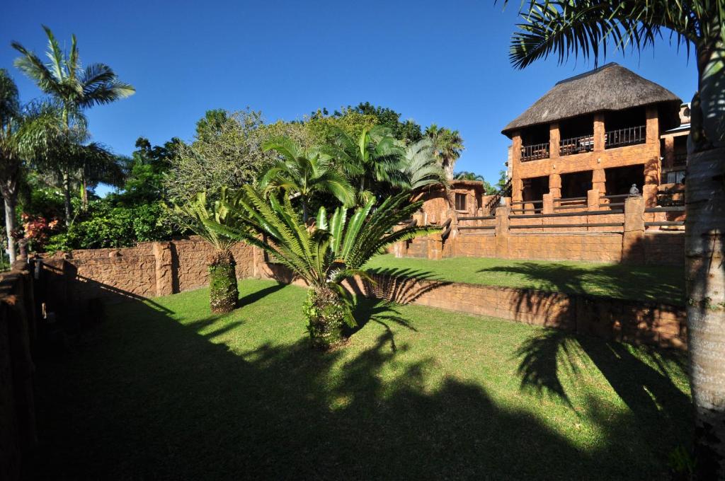 een gebouw met een palmboom voor een muur bij Oppi Rotse Guesthouse in St Lucia