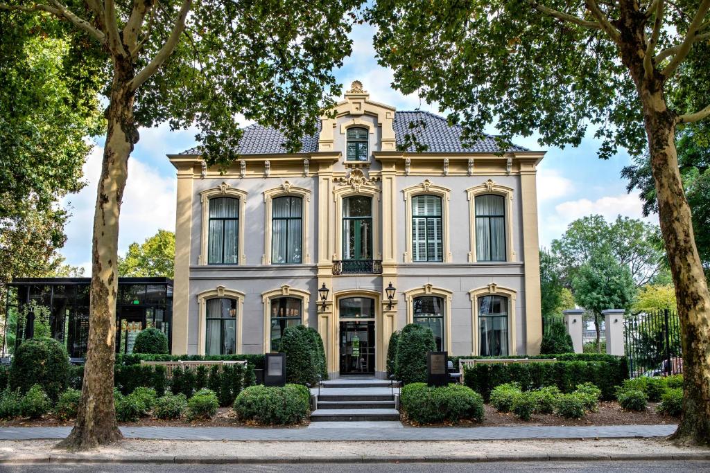 une grande maison blanche avec des arbres devant elle dans l'établissement Pillows Grand Boutique Hotel Ter Borch Zwolle, à Zwolle