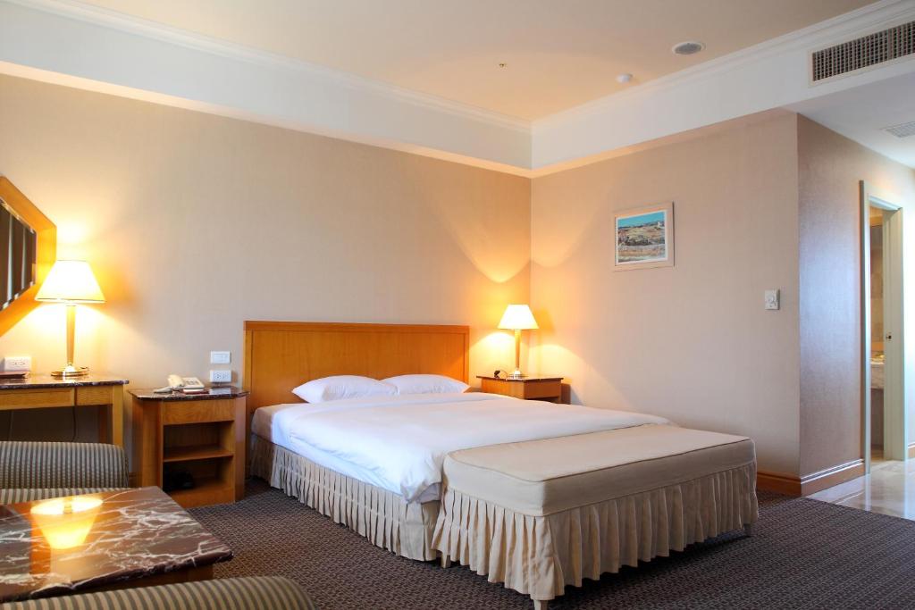 Habitación de hotel con cama grande y escritorio. en Chuto Plaza Hotel en Taoyuan