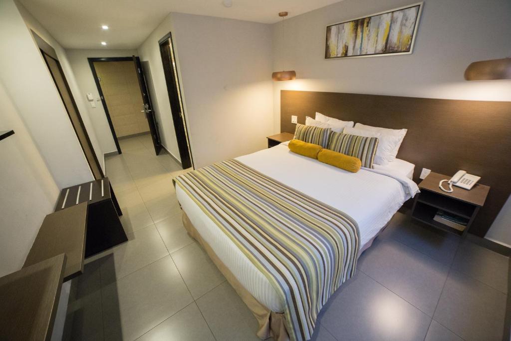 a hotel room with a bed with a yellow pillow at Hotel Ojos Del Rio in Panama City