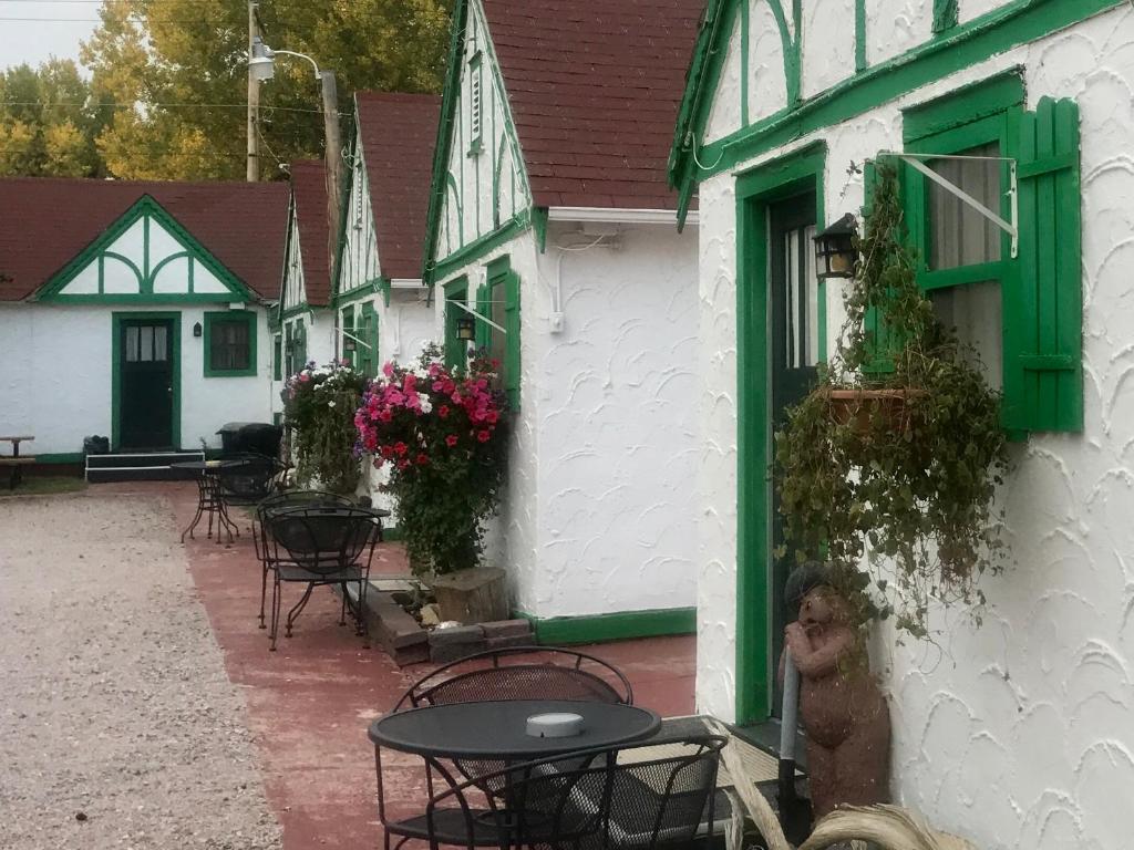 ein weißes Gebäude mit grünen Fenstern, Tischen und Stühlen in der Unterkunft Chalet Motel in Custer