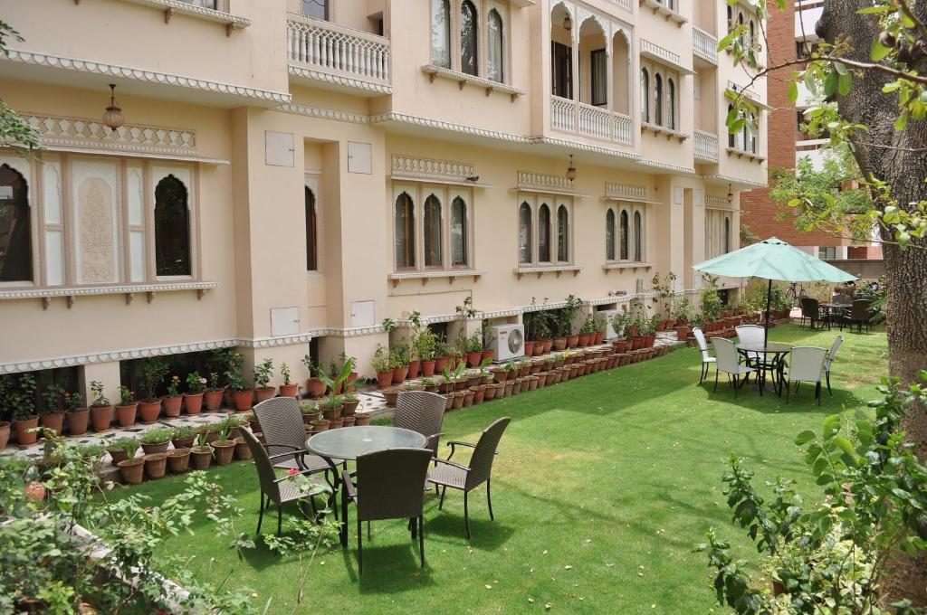 een binnenplaats van een gebouw met stoelen en tafels en een paraplu bij Om Niwas Suite Hotel in Jaipur