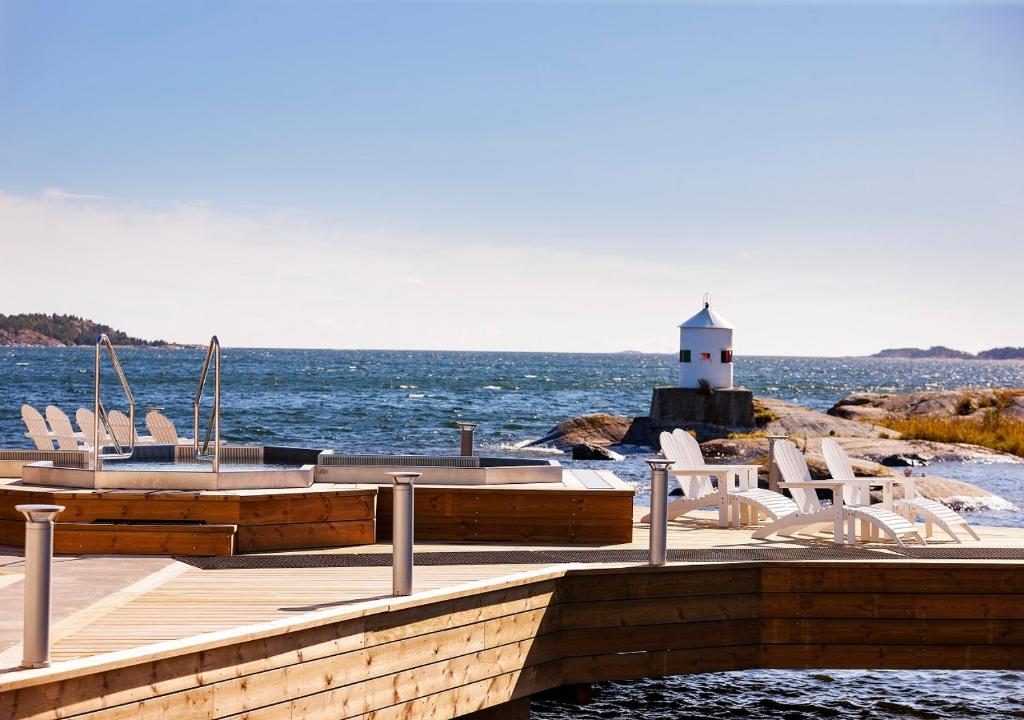 un muelle con sillas y un faro en el agua en Nynäs Havsbad en Nynäshamn