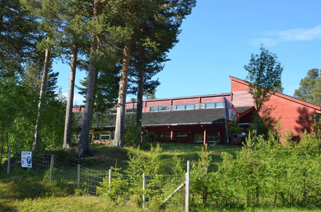 un bâtiment rouge avec une clôture et des arbres dans l'établissement Gjesteheim Havdal, à Sundset