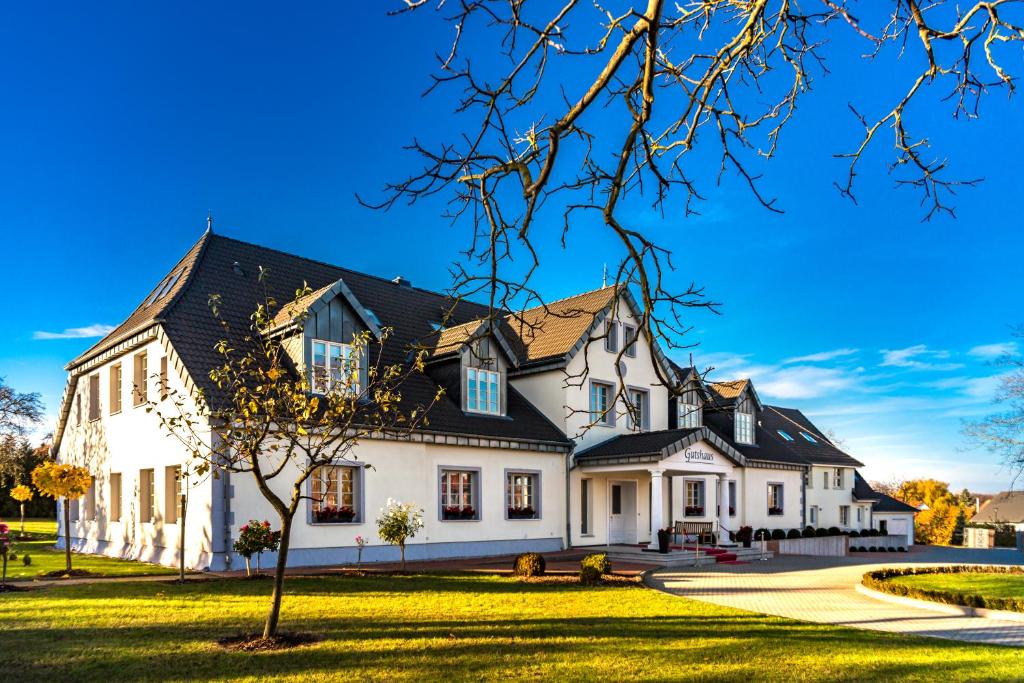 a large white house with a black roof at Pension und Restaurant Gutshaus Kaltenhof in Kaltenhof