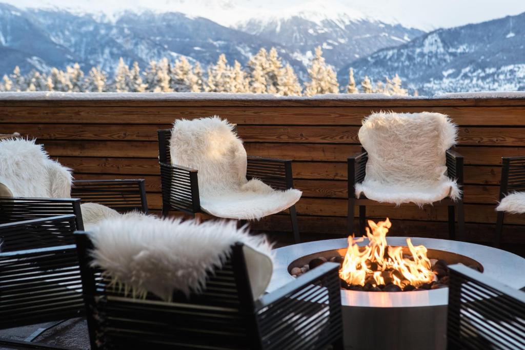 einen Tisch und Stühle mit einer Feuerstelle auf einer Terrasse in der Unterkunft Crans Ambassador in Crans-Montana