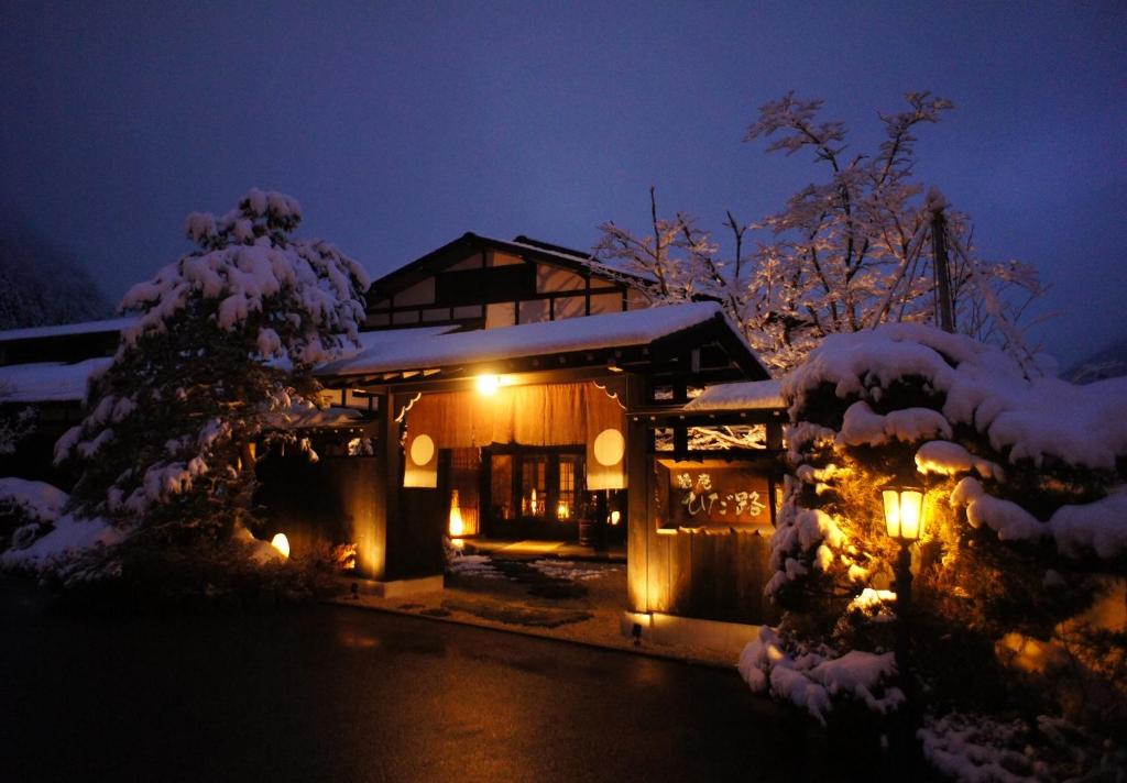 een huis bedekt met sneeuw 's nachts met lichten bij Hidaji (Adult Only) in Takayama