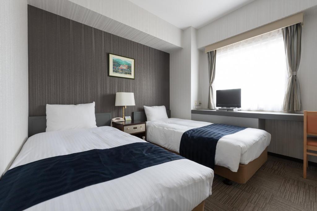 a hotel room with two beds and a tv at Tottori City Hotel in Tottori