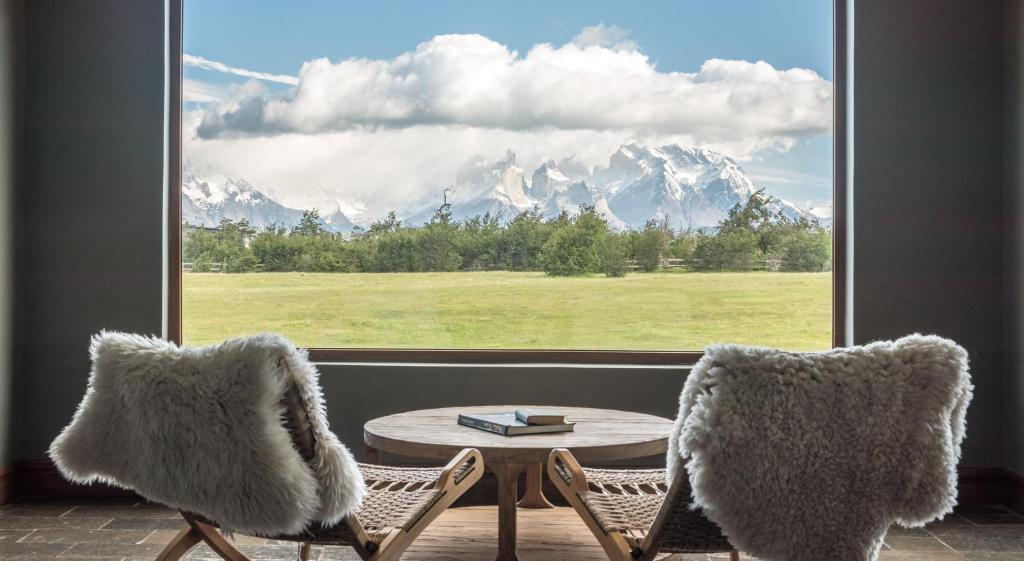 Pokój z 2 krzesłami, stołem i oknem w obiekcie Río Serrano Hotel   Spa w mieście Torres del Paine