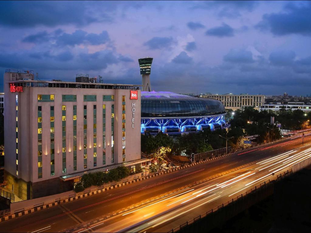 un grande edificio con uno stadio sullo sfondo di notte di ibis Mumbai Airport - An Accor Brand a Mumbai