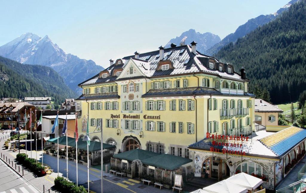 a large yellow building in the middle of a town at Hotel Dolomiti Schloss in Canazei