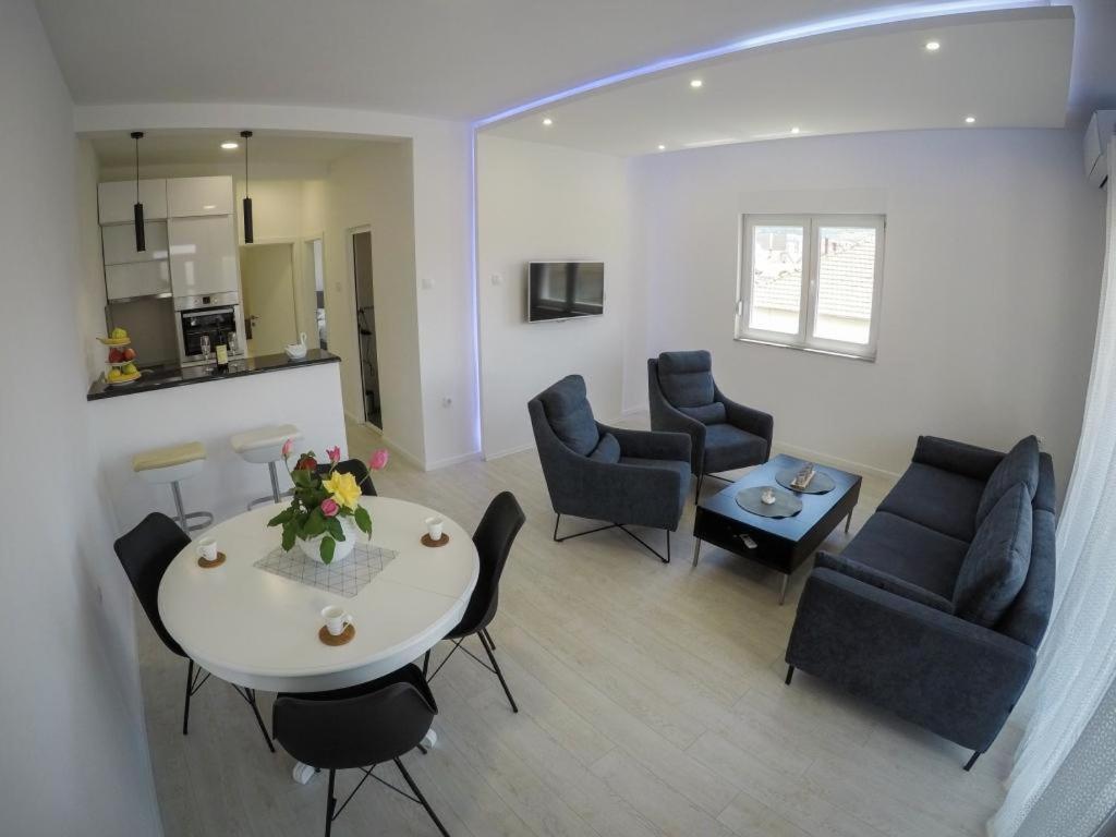 ein Wohnzimmer mit einem Tisch und Stühlen sowie eine Küche in der Unterkunft Apartments Tila in Trebinje