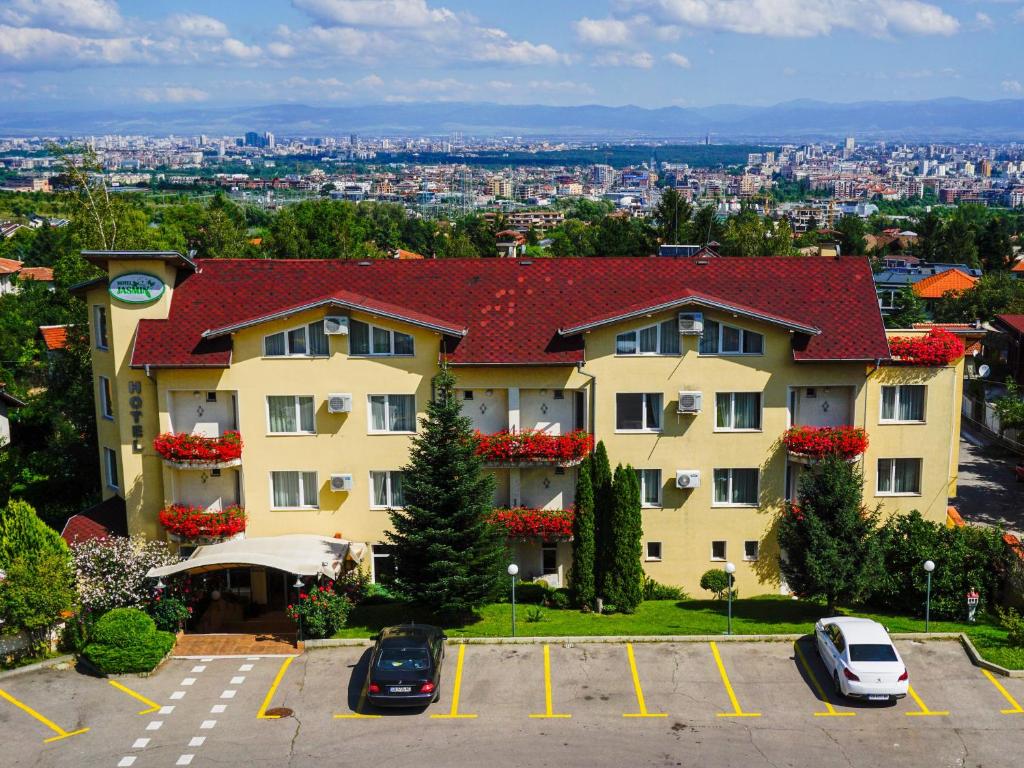 ein großes Gebäude mit Autos auf einem Parkplatz in der Unterkunft Jasmin Hotel in Sofia