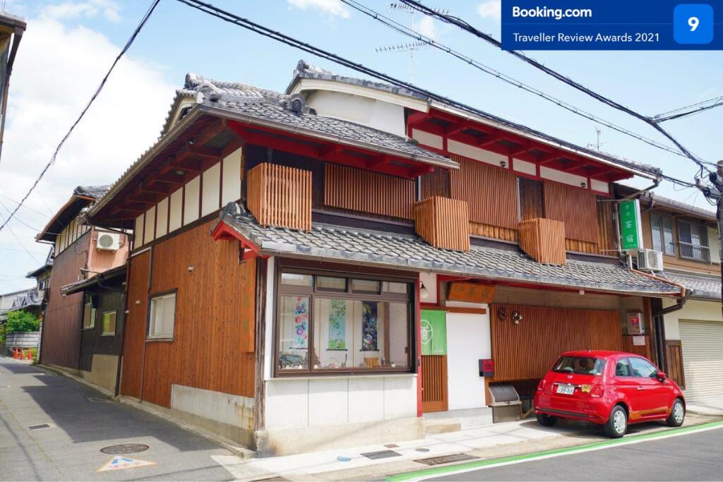 um carro vermelho estacionado em frente a um edifício em Uji Tea Inn em Uji