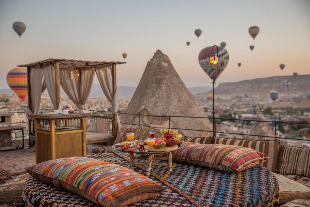 balcón con sofás, mesa y globos de aire caliente en Divan Cave House en Göreme