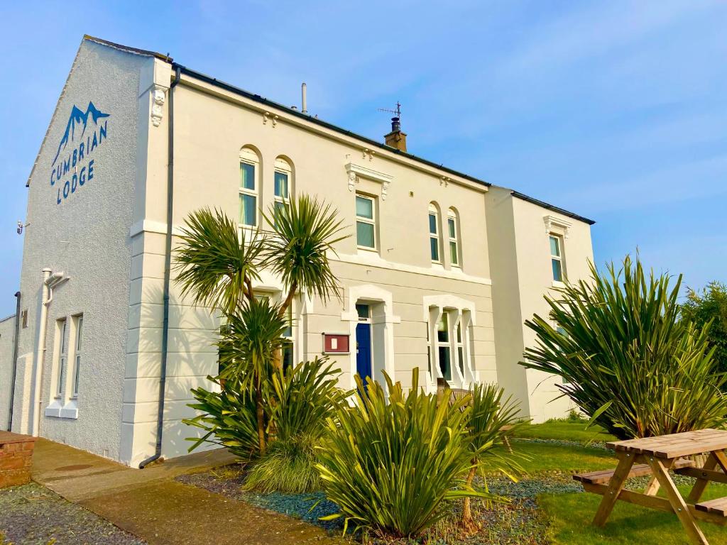 錫斯凱爾的住宿－Cumbrian Lodge，一座白色的建筑,前面有棕榈树