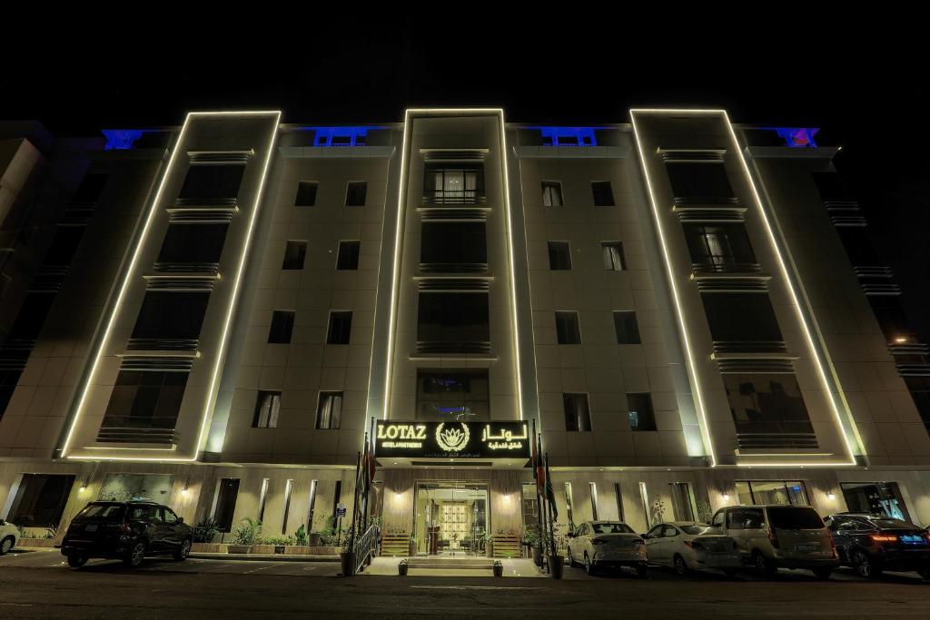 budynek z samochodami zaparkowanymi przed nim w nocy w obiekcie Lotaz Hotel Suites - Al Salamah w mieście Dżudda