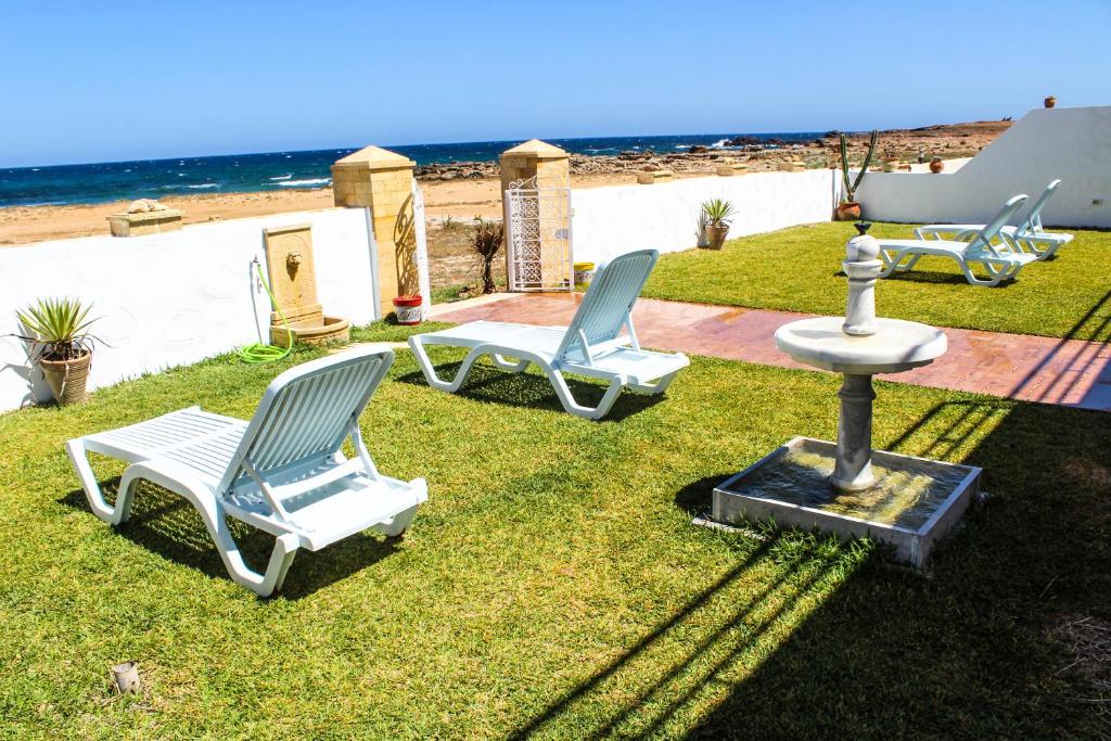 2 chaises et une fontaine sur l'herbe près de la plage dans l'établissement Villa Island Zembra, à El Haouaria