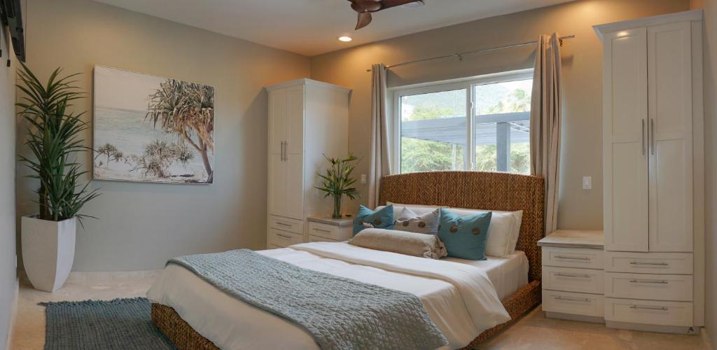 ein Schlafzimmer mit einem großen Bett und einem Fenster in der Unterkunft Sunset Reef St. Kitts in Ottleyʼs