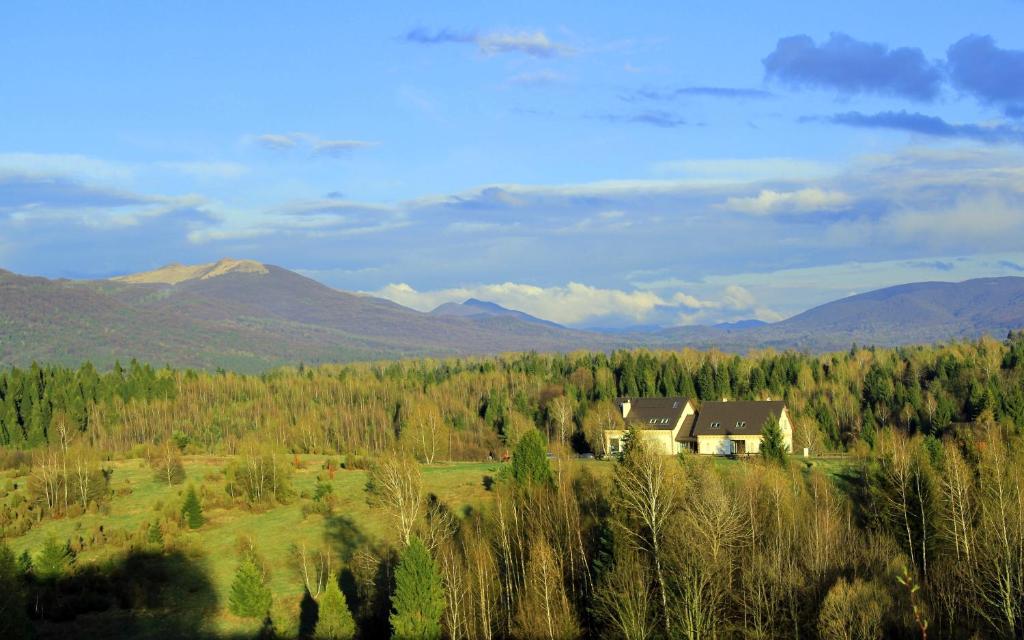 ein Haus auf einem Feld mit Bergen im Hintergrund in der Unterkunft Gościniec Horb in Wetlina