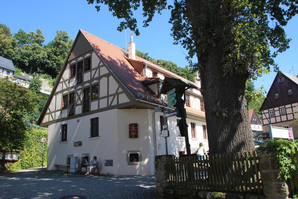 a white house with a brown roof and a tree at Gesundheitshaus Hohnstein in Hohnstein