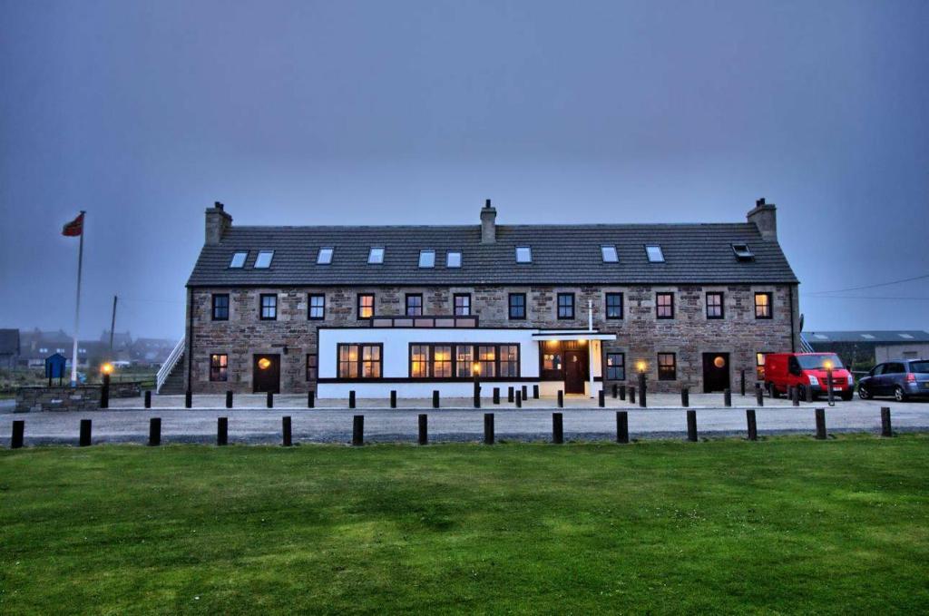 een groot bakstenen gebouw met een gazon ervoor bij The Sands Hotel, Orkney in Burray Village