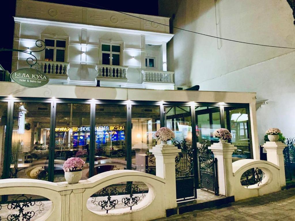 a store front of a building with windows and flowers at Bela Kuka Hotel in Bitola