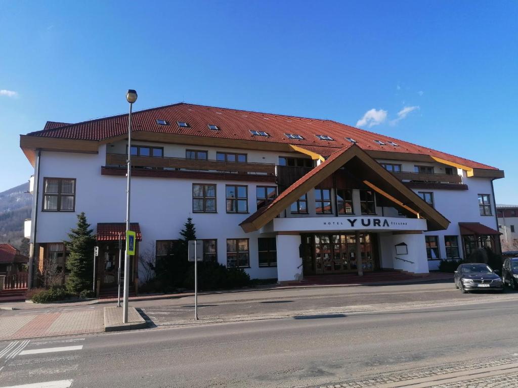 duży biały budynek z czerwonym dachem w obiekcie YURA hotel Čeladná -BAZÉN A SAUNA ZDARMA w mieście Czeladna