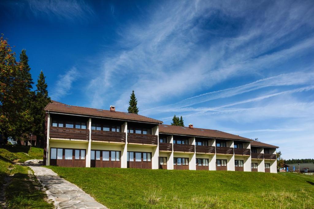 a building on a hill with a blue sky at Hotel Brinje in Zreče