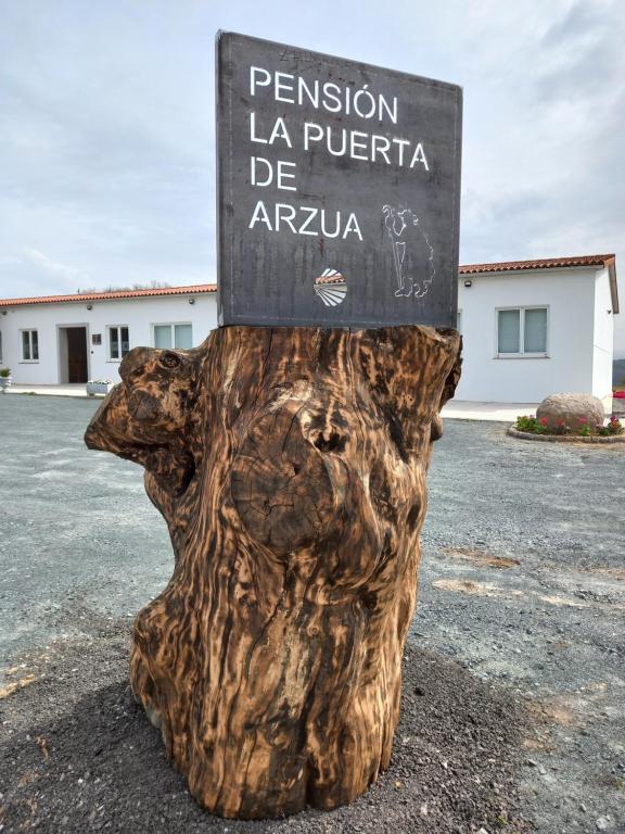 LA PUERTA DE ARZÚA في أرزوا: وجود علامة للجلوس فوق جذع شجرة