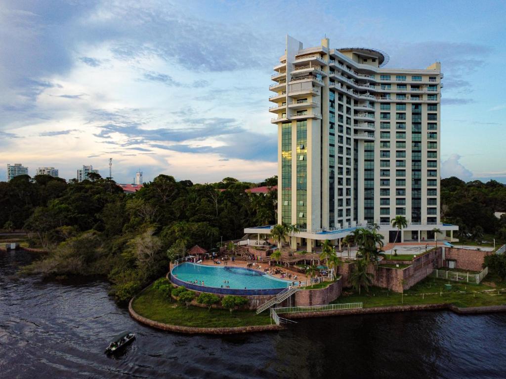 een groot gebouw met een zwembad naast een rivier bij Tropical Executive Hotel in Manaus