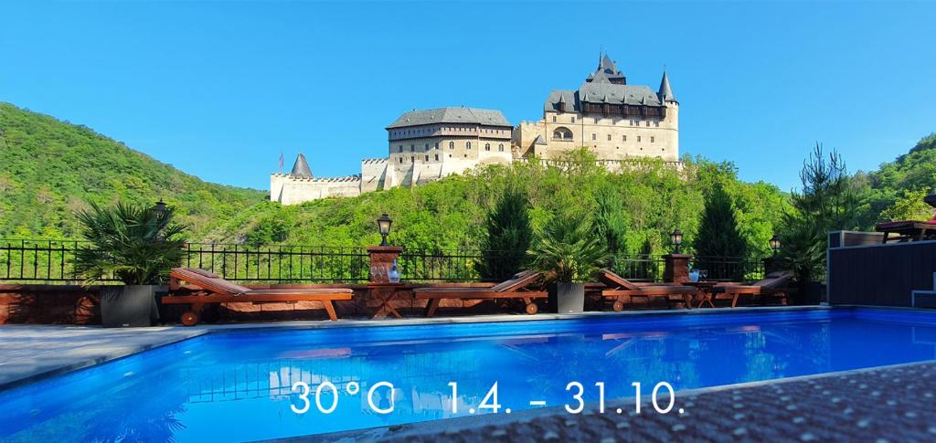 a castle on a hill with a pool in front of it at Hotel Karlštejn & SPA in Karlštejn