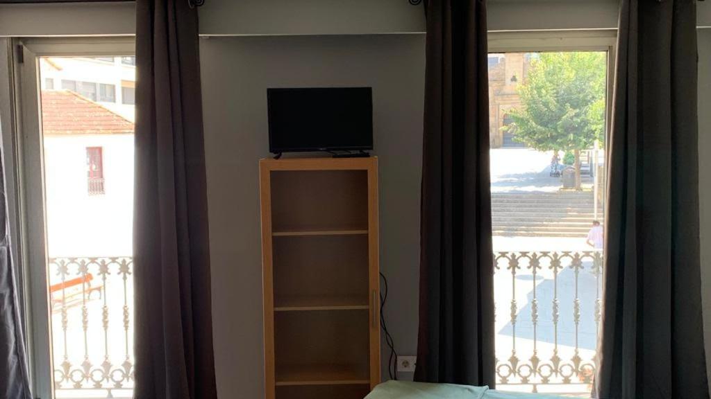 a tv sitting on top of a book shelf next to a window at APARTAMENTO FONTE DO CRISTO in Porriño