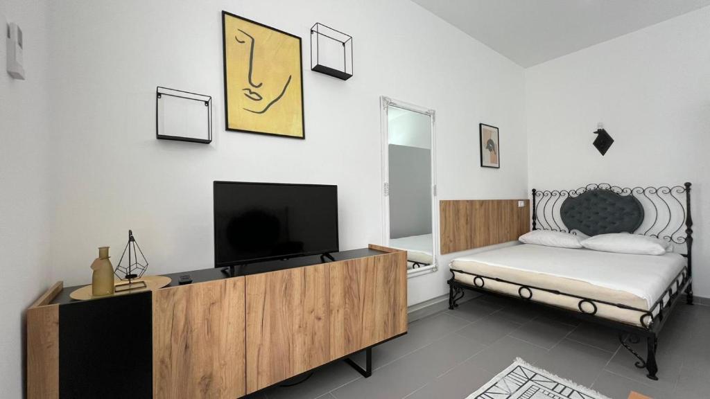 a bedroom with a bed and a tv on a wall at Apartmani Aurora in Tuzla