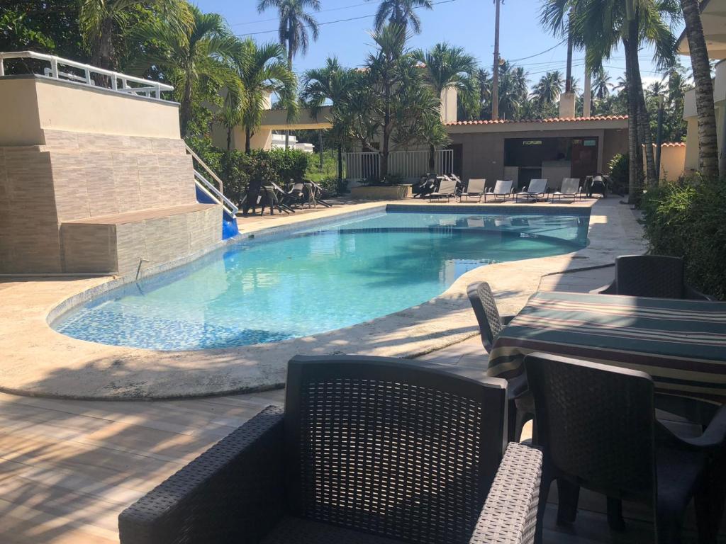 - une piscine avec une table et des chaises dans un complexe dans l'établissement Hotel Cambri, à Nagua