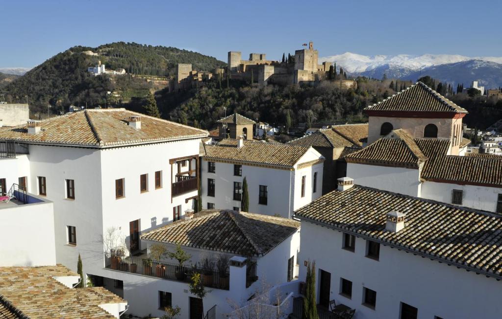 una vista de los tejados de las casas con un castillo en el fondo en Smart Suites Albaicin en Granada