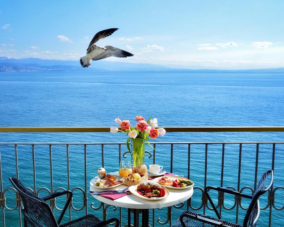 a table with food and a bird flying over the water at Hotel Savoy in Opatija