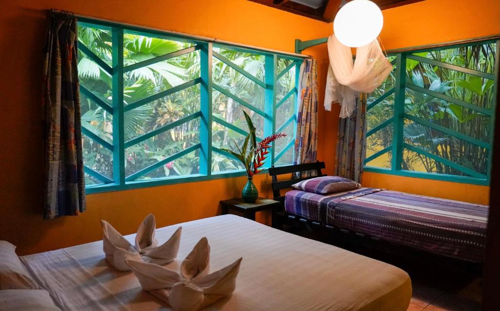 a bedroom with two beds and a large window at Cabinas Guarana in Puerto Viejo