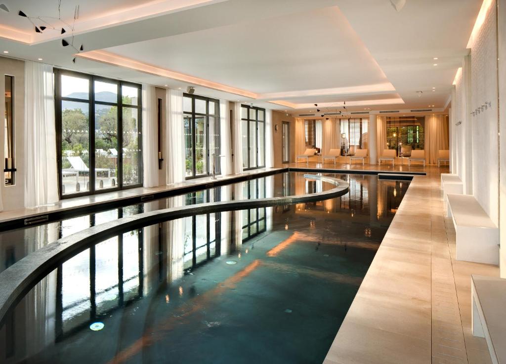 a pool in the middle of a building with windows at Domaine du Mas De Pierre in Saint Paul de Vence