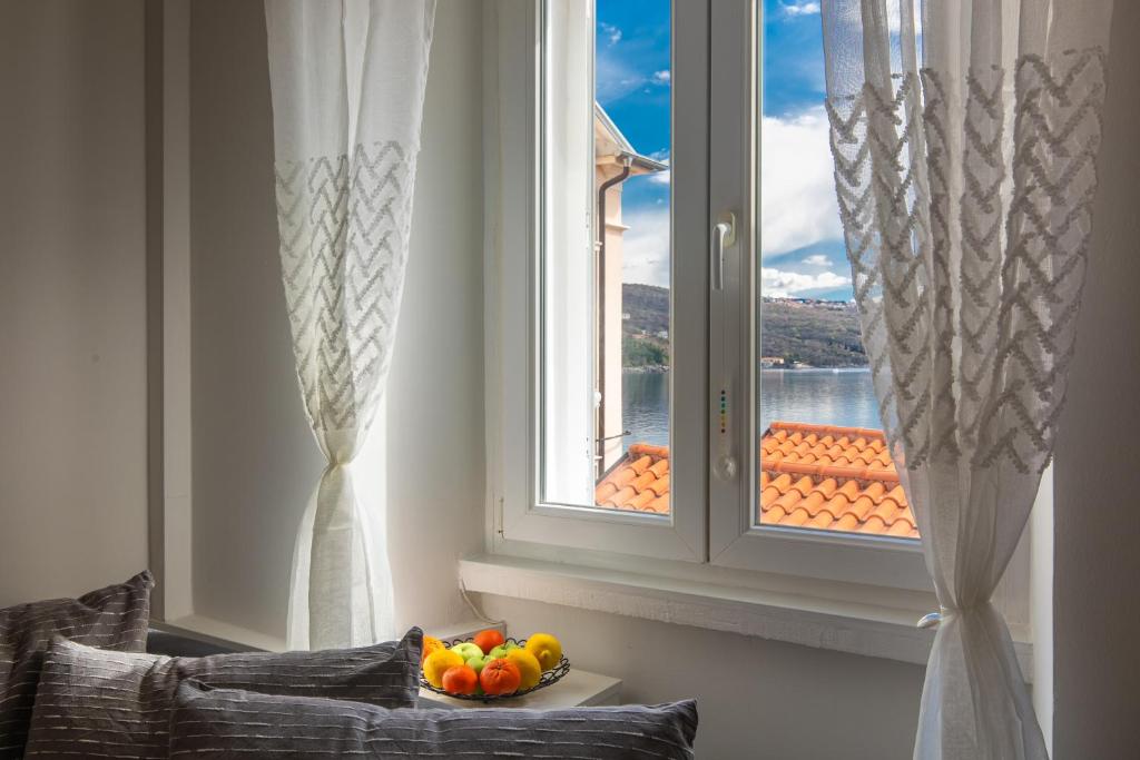 a window with a bowl of fruit on a table in front of it at Apartman Žana in Opatija