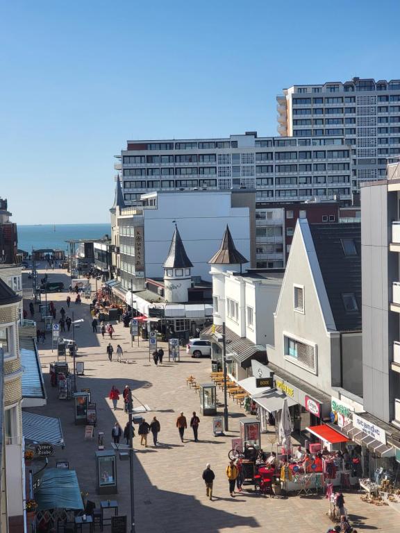 un grupo de personas caminando por una calle con edificios en Hotel von Stephan, en Westerland