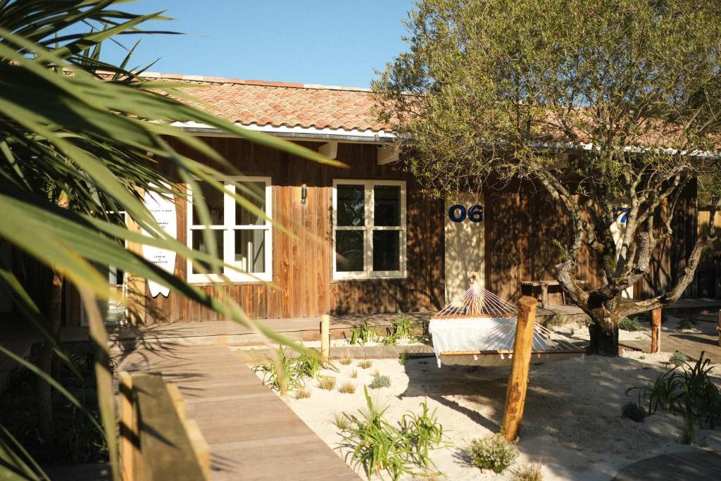 a wooden house with a bench in front of it at Hotel des Dunes in Cap-Ferret